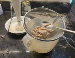 Sieving cooked chicken to make a paste